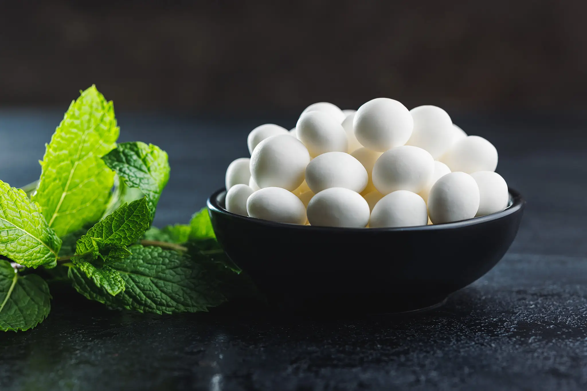 bowl-of-white-candies-with-fresh-mint-leaves-2026-03-24-04-04-03-utc Formaggio prodotto con caglio vegetale, alternativa ideale per la produzione di formaggi adatti ai vegetariani.